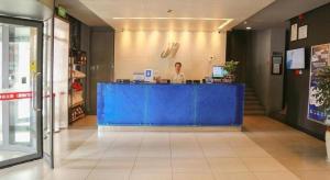 een vrouw die achter een blauwe toonbank in een winkel staat bij Jinjiang Inn Yueyang Railway Station in Yueyang