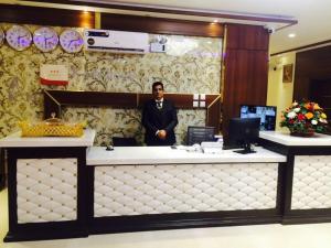 a man standing behind a counter in a lobby at Kadi Hotel in Najran