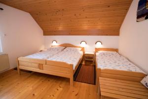 2 Betten in einem Zimmer mit Holzdecken in der Unterkunft Turistična Kmetija Gartner 3a in Bohinj