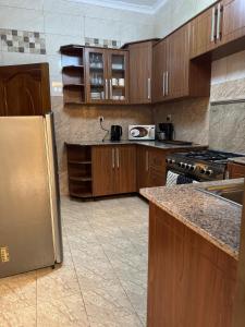 a kitchen with wooden cabinets and a stainless steel refrigerator at Dafrican BnB villa in Kigali