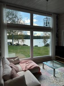 a living room with a couch and a large window at Log cabin by the lake in Pieksamaki