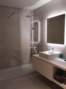 un bagno con lavandino, doccia e specchio di Lagoa Princess Condo a Lagoa