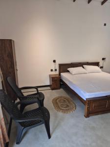 a bedroom with a bed and a chair and a table at the cinnamon home in Koggala