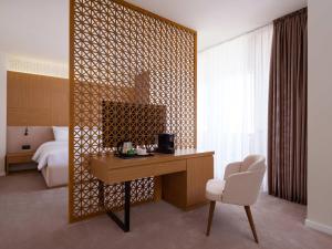 Zimmer mit einem Schreibtisch, einem Bett und einem Schlafzimmer. in der Unterkunft Mercure Bukhara Old Town in Buxoro + 64 Fotos