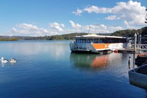 an orange and white boat on a lake with swans at 2Br Apartment, Pool, 12 mins to Airport in Bilambil Heights