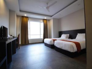 een hotelkamer met twee bedden en een raam bij Hotel Bhutan Ga Me Ga in Phuntsholing
