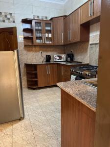 a kitchen with wooden cabinets and a stainless steel refrigerator at Dafrican BnB in Kigali +25 photos