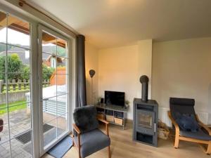 een woonkamer met een open haard, een stoel en een televisie bij Apartment in Katschberg near Ski Slopes in Sankt Margarethen im Lungau