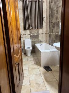 a bathroom with a toilet and a tub and a sink at Dafrican BnB in Kigali