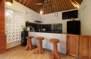 eine Küche mit einer Bar mit drei Holzhockern in der Unterkunft 1 Bedroom Pool Villa Bebandem Karangasem in Bebandem