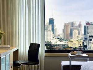 a hotel room with a view of a city from a window at Grand Mercure Bangkok Atrium in Bangkok