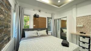 Двухкомнатный дом на Бангтао ДИН في Ban Thalat Choeng Thale: غرفة نوم بها سرير وجدار من الطوب