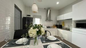 Двухкомнатный дом на Бангтао ДИН في Ban Thalat Choeng Thale: مطبخ مع طاولة عليها مزهرية من الزهور +33 صورة