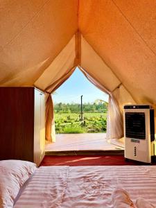 a room with a bed in a tent with a window at The Lake Farm - Dak Lak in Buon Ma Thuot