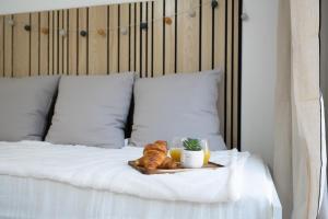 a tray with a loaf of bread and two drinks on a bed at Aréva - Provençal - Climatisé - Parking in Ventabren
