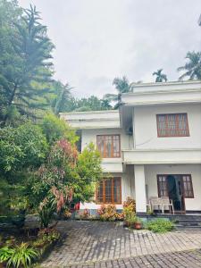 una casa blanca con árboles delante en Leela, en Green Island