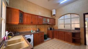 a kitchen with wooden cabinets and a sink and a dishwasher at Sultan Beach House in Muscat