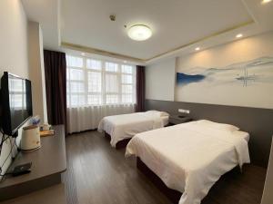 a hotel room with two beds and a flat screen tv at GreenTree Inn HanZhong Railway Station Beiyihuan Road Express Hotel in Shima