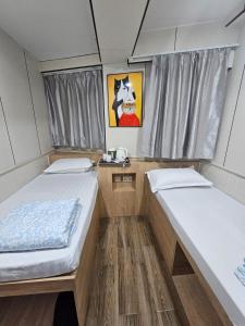 two beds in a small room with a painting at K & B Hostel in Hong Kong