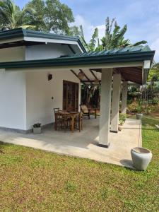 a patio with a roof and a table and chairs at the cinnamon home in Koggala