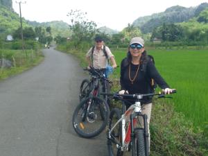 a man and a woman on bikes on a road at Homestay Rammang Rammang in Baloci