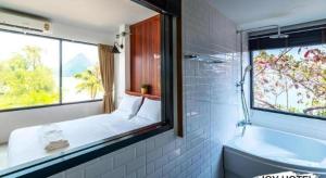 baño con bañera, cama y ventana en Joy Hotel, en Khao Khan Kradaj 67 fotos más