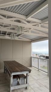 Una habitación grande con una mesa de madera en un balcón. en Point View Selfcatering, en Mossel Bay