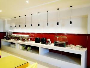 a kitchen with red walls and white counter tops at GreenTree Inn Jiangsu Xuzhou Jinshan Bridge Building Jinqiao Road Express Hotel in Xuzhou