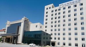 een wit gebouw met een auto ervoor geparkeerd bij Zhangjiagang Jiangnan Garden Hotel in Xiwujieqiao