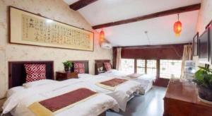 een slaapkamer met drie bedden en een schilderij aan de muur bij Pingyao Yufengheng Hotel in Pingyao