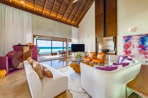 a living room with white furniture and a view of the ocean at OZEN LIFE MAADHOO - Luxury All Inclusive with Free Transfers in South Male Atoll