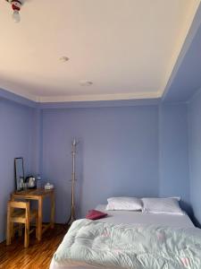 a bedroom with blue walls and a bed and a table at DIPSAGAR Hotel And Lodge in Bandīpur