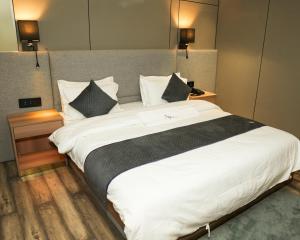 una cama blanca grande en una habitación de hotel en Hotel Aroma Inn, en Morādābād