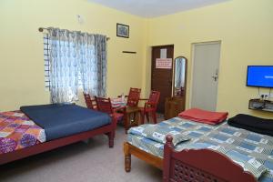 a bedroom with two beds and a table and chairs at Coorg Mountain View in Madikeri