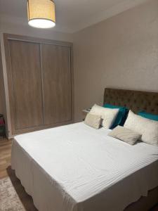 une chambre avec un grand lit avec des draps et des oreillers blancs dans l'établissement Nice apartment with terrace overlooking pool, à Benslimane