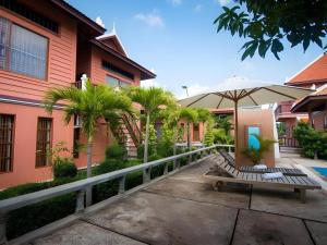 a bench with an umbrella in front of a building at Sambopich Chenla Hotel in Phumĭ Achary Leăk