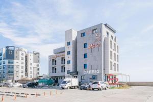 a building with cars parked in a parking lot at HOTEL52 in Seogwipo