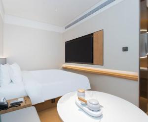 a room with a bed and a table with a tv at JI Hotel Beijing Shangdi Nongda South Road in Beijing