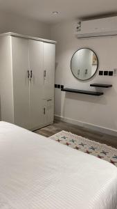 Un dormitorio con una cama blanca y un espejo. en شقة بغرفة وصالة, en Riad 2 fotos más