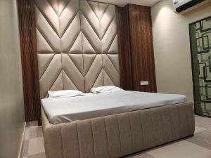 a bedroom with a large bed with a padded headboard at Hotel O THE ERA INFINITY HOTEL in Faithfulganj +15 photos