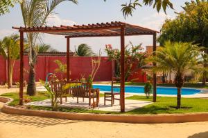 a pergola with a table and chairs next to a pool at Pousada Villa Botânica in Aracati