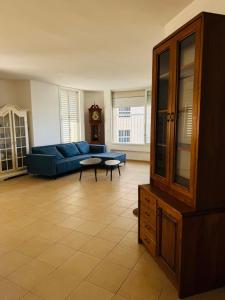 a living room with a blue couch and a clock at Beach apartment on Nitsa street in Netanya