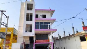 a tall white building with a clock tower at Hotel O Surya Hotel in Kākori