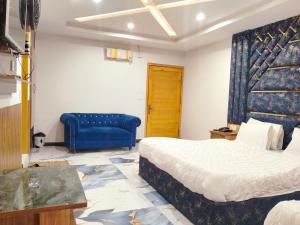 a bedroom with a bed and a blue couch at Hotel One Ten in Murree
