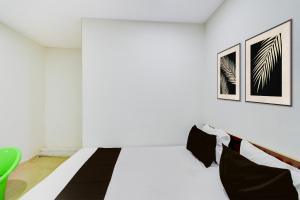 a white room with a bed and a green chair at Hotel O S V Residency in Vidya Nagar