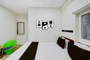 a white bedroom with a bed and a green chair at Hotel O S V Residency in Vidya Nagar +21 photos