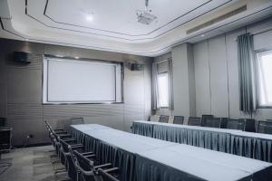 a conference room with tables and chairs and a white screen at Jinjiang Metropolo Hotel Nanjing Jiangning Binjiang Development Zone in Qingxiu