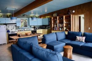 a living room with blue couches and a kitchen at Stunning Beachfront Cabin with Barbecue and Hot-tub in Otis, Oregon in Three Rocks