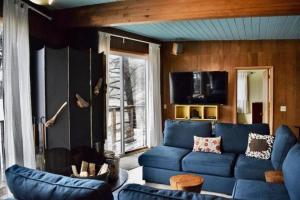 a living room with a blue couch and a tv at Stunning Beachfront Cabin with Barbecue and Hot-tub in Otis, Oregon in Three Rocks +46 photos