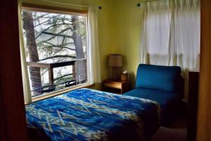 a bedroom with a blue bed and a window at Stunning Beachfront Cabin with Barbecue and Hot-tub in Otis, Oregon in Three Rocks